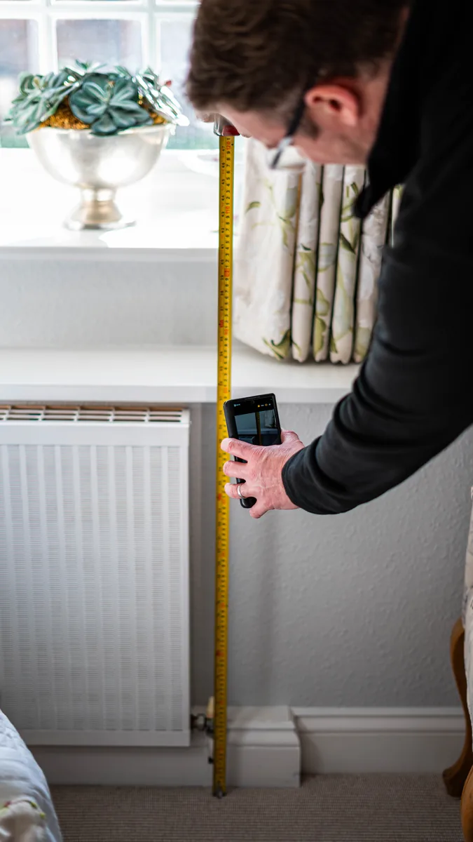 M&W engineer measuring a radiator during a room-by-room heat survey